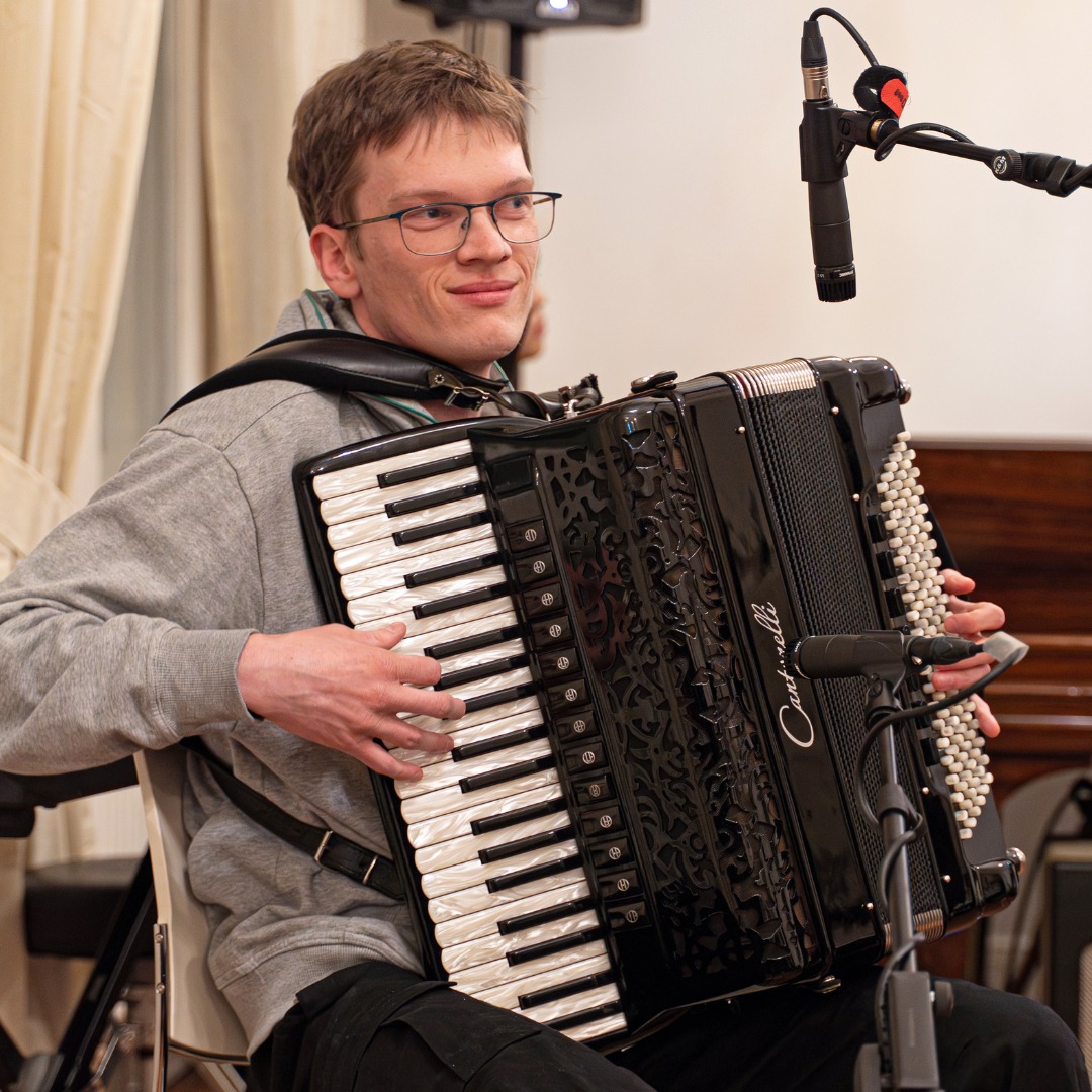 Lennart Desler spielt Akkordeon auf einer Bühne vor einem Mikrofon.