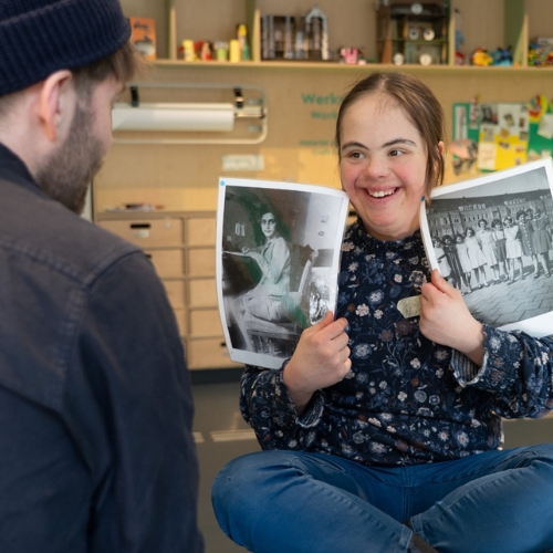 Frau zeigt strahlende Schwarz-Weiß-Fotos einer anderen Person.