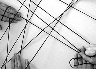 Hände spannen ein Netz aus schwarzen Fäden